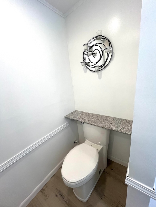 bathroom with hardwood / wood-style floors, toilet, and crown molding