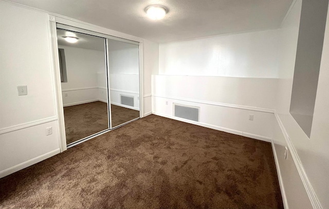 unfurnished bedroom featuring a closet and dark carpet