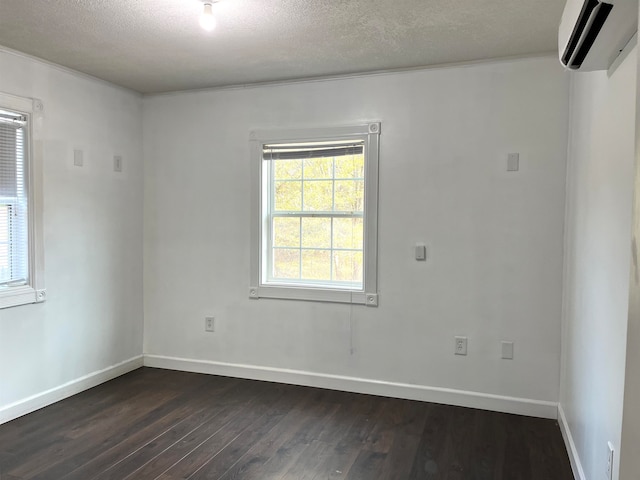 empty room with a wall unit AC, dark hardwood / wood-style flooring, and a textured ceiling