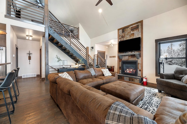 living room featuring a fireplace, dark hardwood / wood-style floors, high vaulted ceiling, and ceiling fan