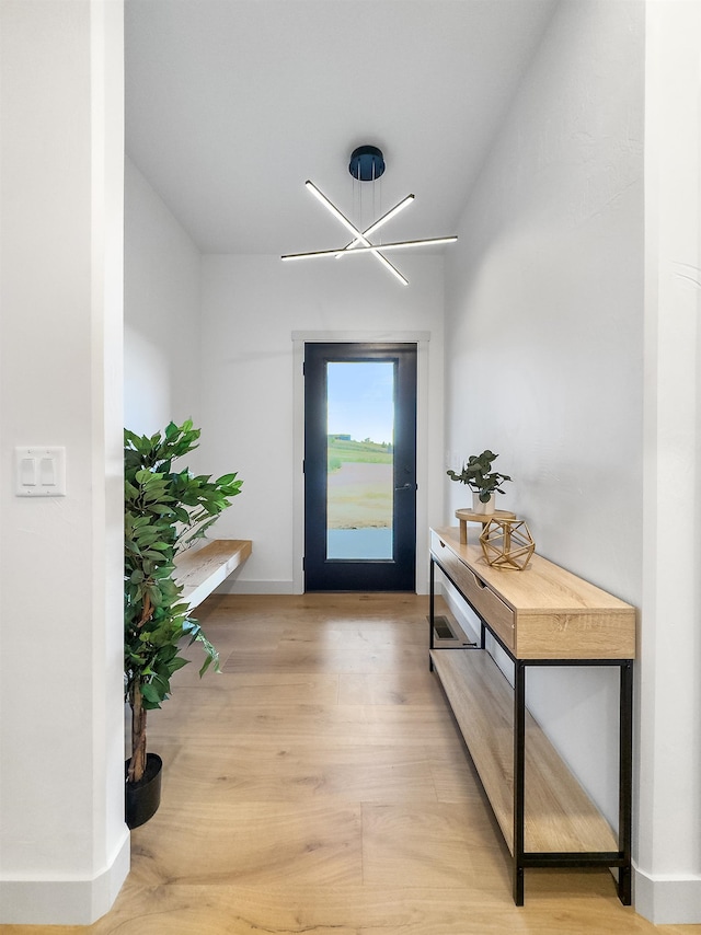 doorway with an inviting chandelier and light hardwood / wood-style flooring