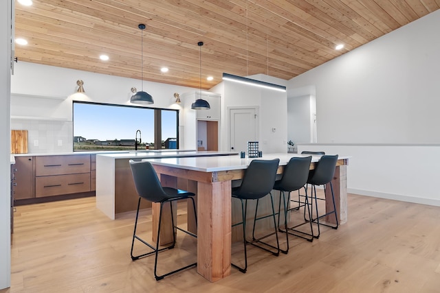 kitchen featuring a large island, light wood-type flooring, hanging light fixtures, and wooden ceiling