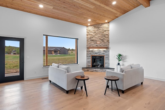 living room with wooden ceiling, a stone fireplace, high vaulted ceiling, beamed ceiling, and light wood-type flooring