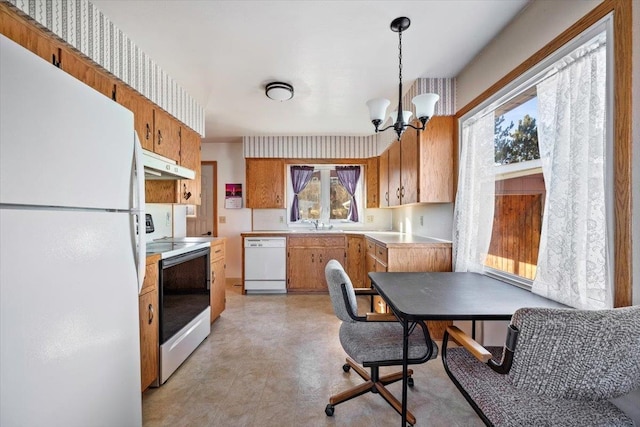 kitchen featuring white appliances, decorative light fixtures, and an inviting chandelier