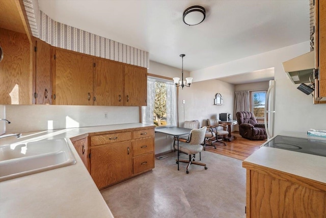 kitchen with pendant lighting, sink, light wood-type flooring, a notable chandelier, and white fridge