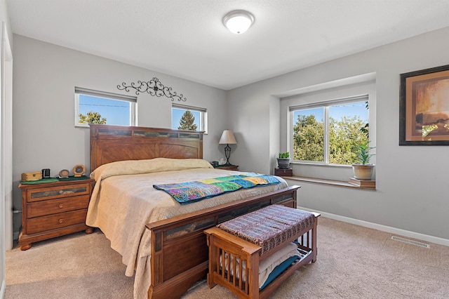 bedroom with light colored carpet and multiple windows