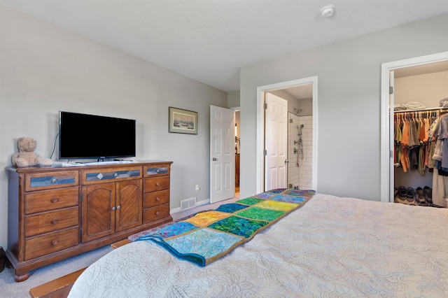 bedroom featuring light carpet, a walk in closet, a closet, and connected bathroom