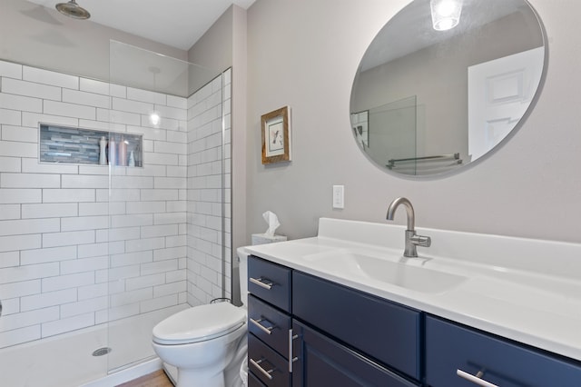 bathroom featuring a tile shower, vanity, and toilet