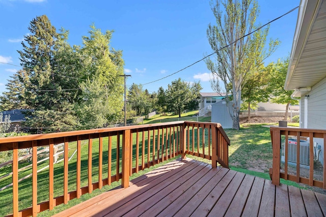 wooden deck featuring a lawn, a shed, and central AC