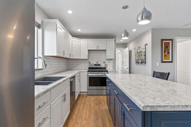 kitchen with appliances with stainless steel finishes, light wood-type flooring, blue cabinets, sink, and white cabinets