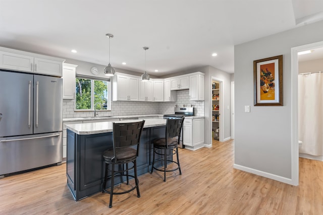 kitchen with sink, stainless steel appliances, pendant lighting, white cabinets, and light wood-type flooring