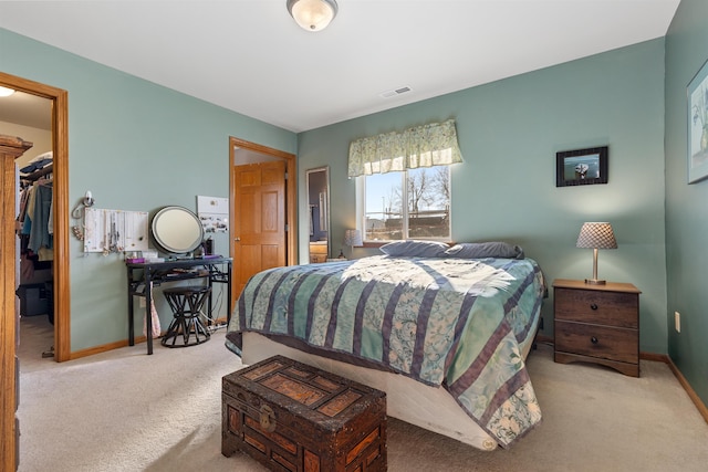 bedroom with a walk in closet, light colored carpet, and a closet