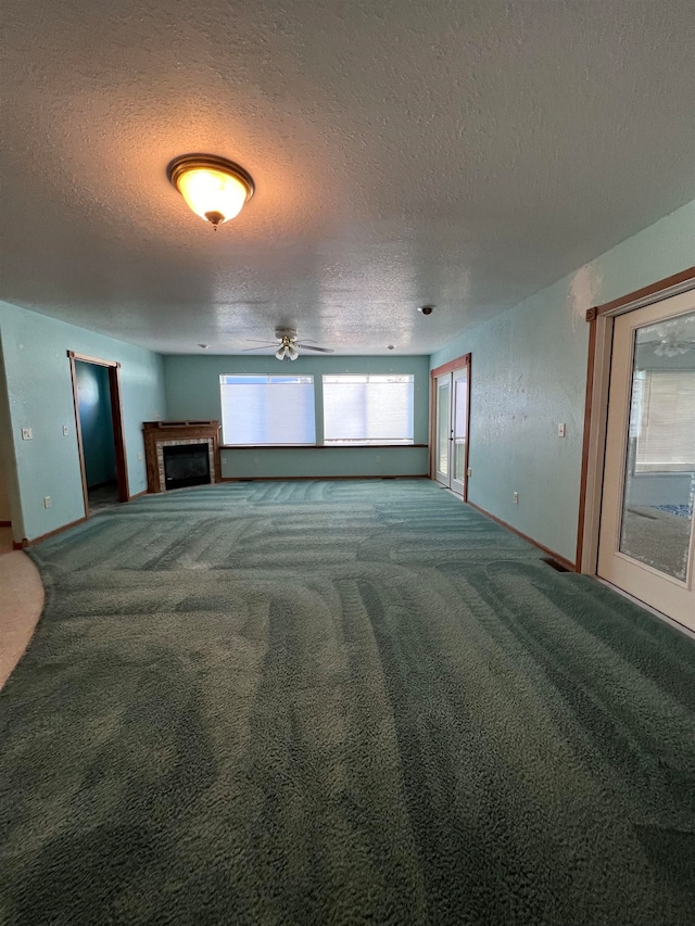 unfurnished living room with carpet, ceiling fan, and a textured ceiling