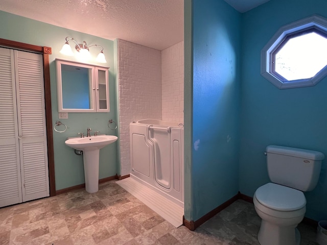 bathroom with sink, toilet, and a textured ceiling