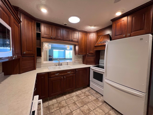 kitchen with sink, an inviting chandelier, backsplash, white appliances, and custom range hood