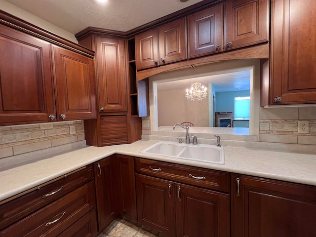 kitchen featuring backsplash, decorative light fixtures, an inviting chandelier, and sink