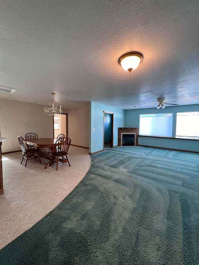 living room featuring carpet, ceiling fan with notable chandelier, and a textured ceiling