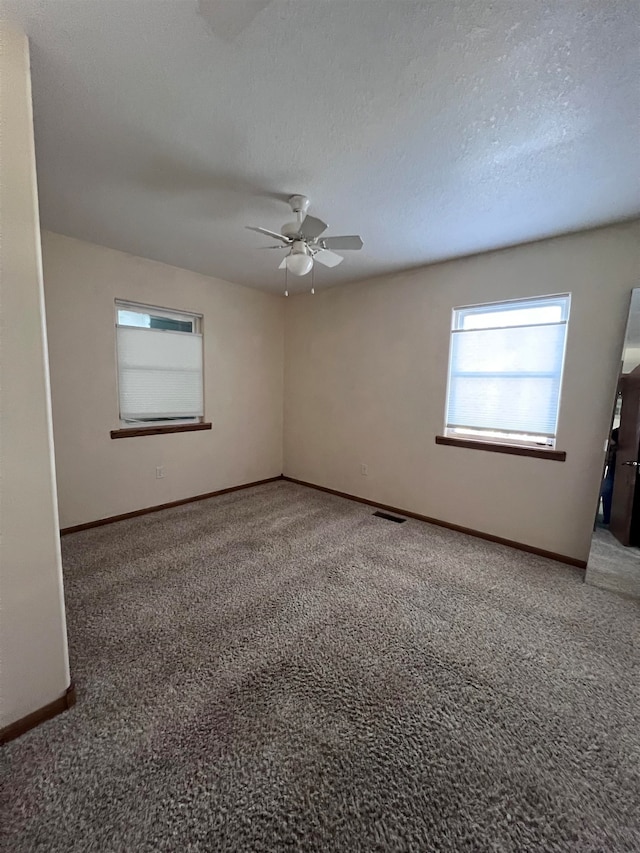 empty room with ceiling fan, carpet floors, and a textured ceiling