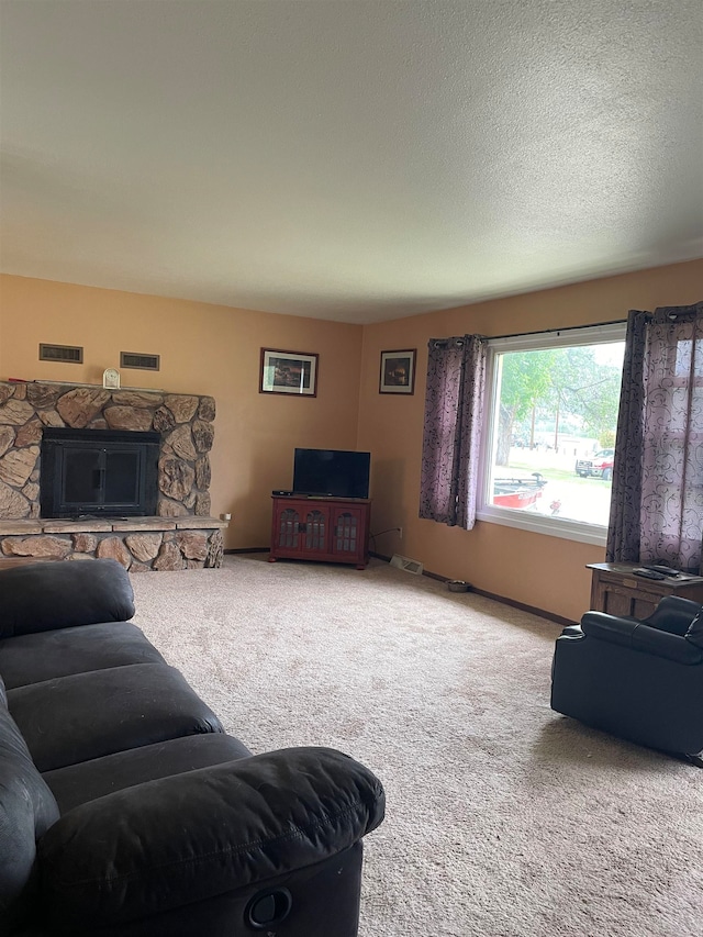 living room featuring carpet, a stone fireplace, and a textured ceiling