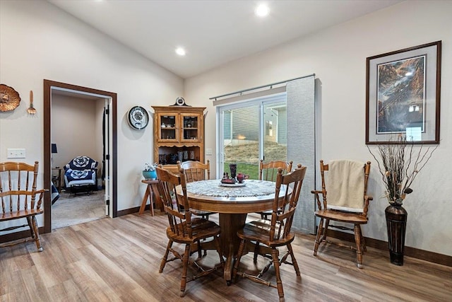 dining area with light hardwood / wood-style floors and vaulted ceiling