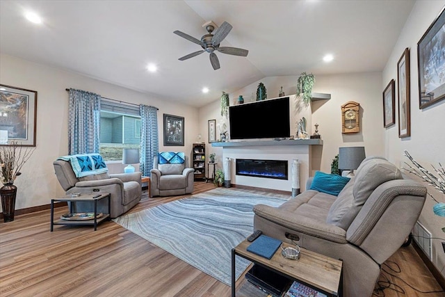 living room featuring light hardwood / wood-style floors, vaulted ceiling, and ceiling fan