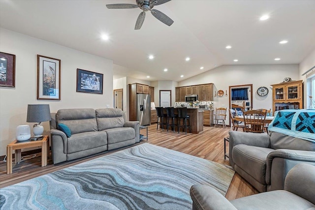 living room with ceiling fan, lofted ceiling, and light wood-type flooring