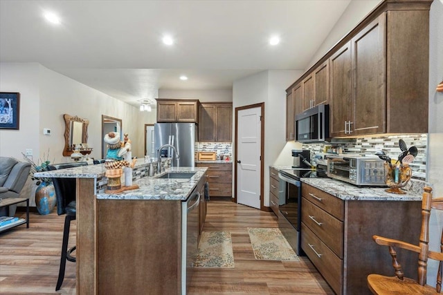 kitchen featuring light hardwood / wood-style floors, sink, stainless steel appliances, and a kitchen island with sink