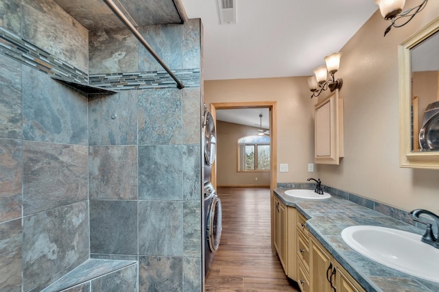 bathroom with wood-type flooring, vanity, lofted ceiling, and stacked washer / drying machine