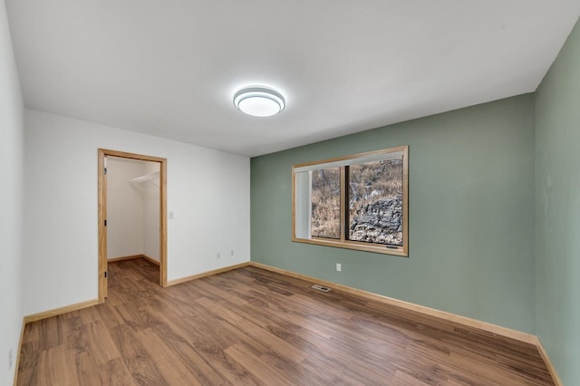 unfurnished bedroom with a walk in closet, a closet, and light wood-type flooring