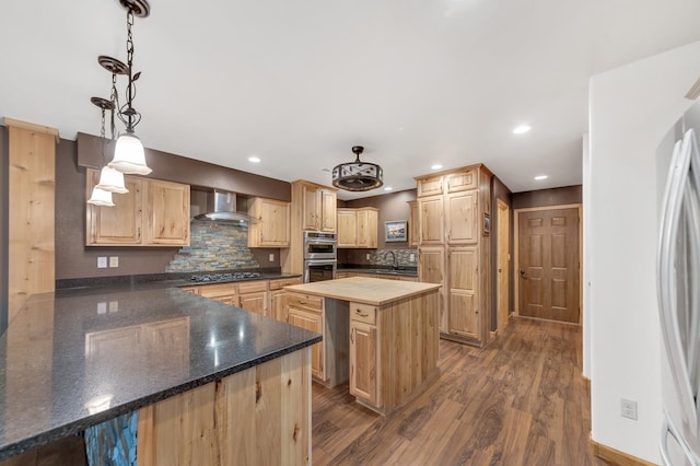 kitchen featuring a center island, wall chimney range hood, hanging light fixtures, dark hardwood / wood-style floors, and tasteful backsplash