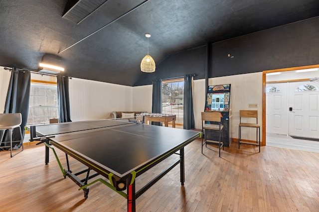 game room with a textured ceiling, a healthy amount of sunlight, light hardwood / wood-style flooring, and vaulted ceiling