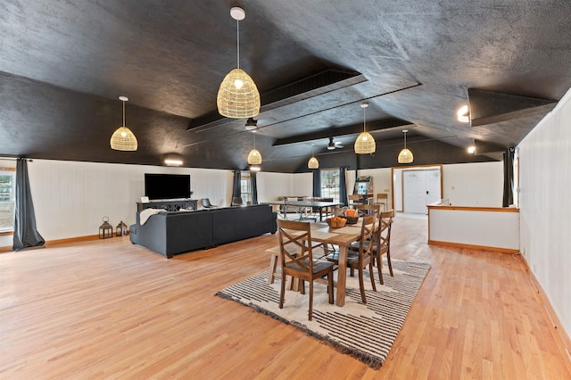 dining space featuring light hardwood / wood-style floors, a textured ceiling, and vaulted ceiling