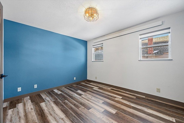 empty room featuring a textured ceiling and dark wood-type flooring