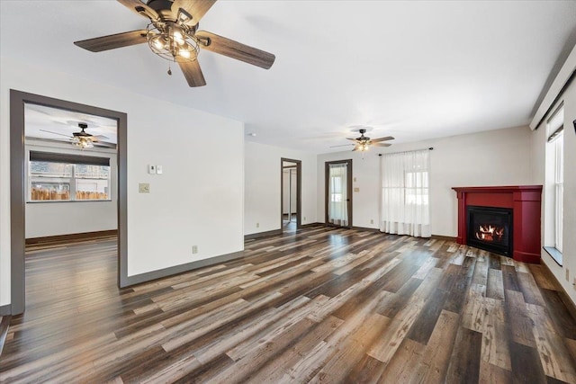 unfurnished living room with ceiling fan, dark wood-type flooring, and a healthy amount of sunlight