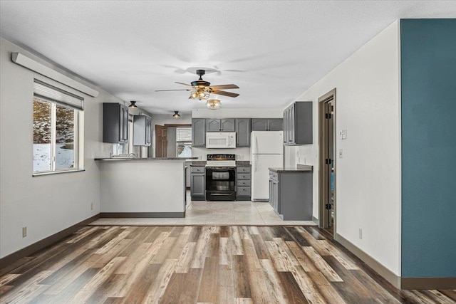 kitchen featuring white appliances, ceiling fan, gray cabinets, dark hardwood / wood-style flooring, and kitchen peninsula