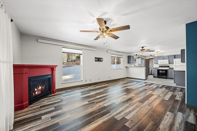 unfurnished living room featuring dark hardwood / wood-style floors, ceiling fan, and a textured ceiling