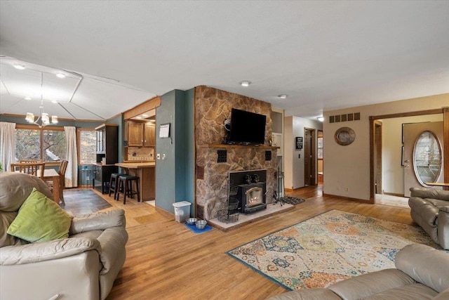 living room featuring light hardwood / wood-style floors, a wood stove, and a notable chandelier