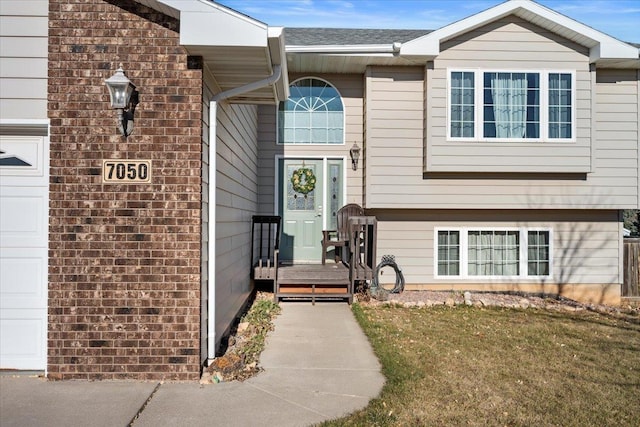 view of exterior entry with a garage and a lawn