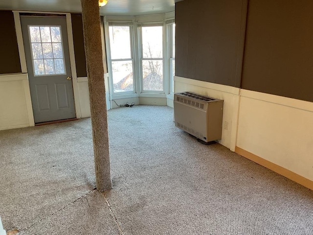 unfurnished living room featuring heating unit and light colored carpet