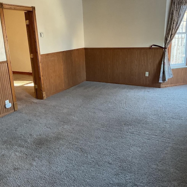 carpeted spare room featuring wood walls