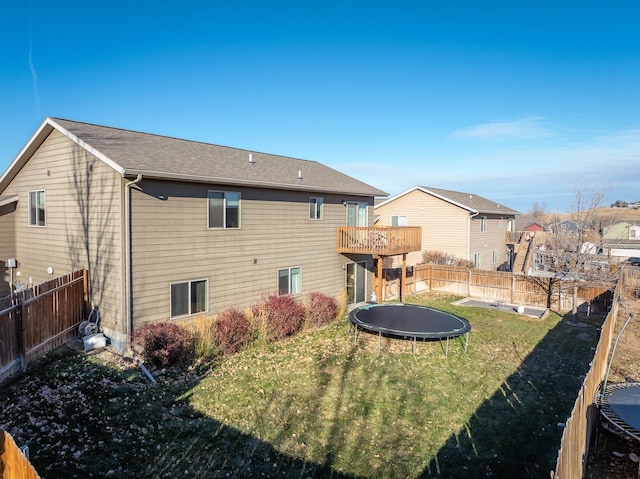 back of property with a lawn and a trampoline