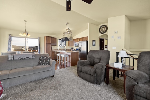 living room with carpet, ceiling fan with notable chandelier, sink, and vaulted ceiling