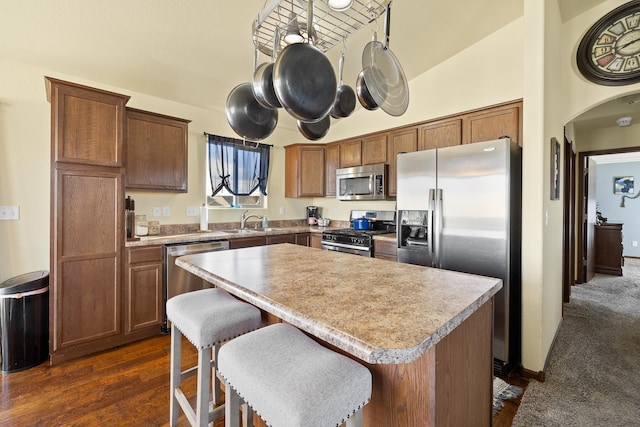 kitchen with sink, stainless steel appliances, dark hardwood / wood-style flooring, vaulted ceiling, and a kitchen island