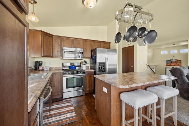 kitchen with decorative light fixtures, dark wood-type flooring, vaulted ceiling, and appliances with stainless steel finishes