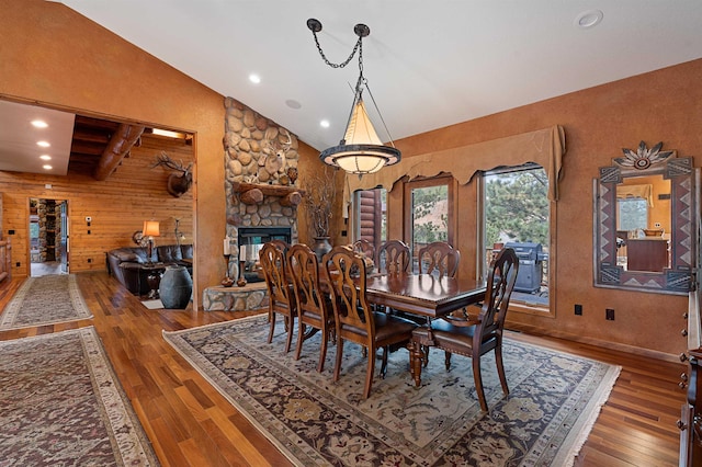 dining room with a fireplace, vaulted ceiling, and hardwood / wood-style flooring