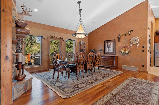 dining room with high vaulted ceiling and hardwood / wood-style flooring