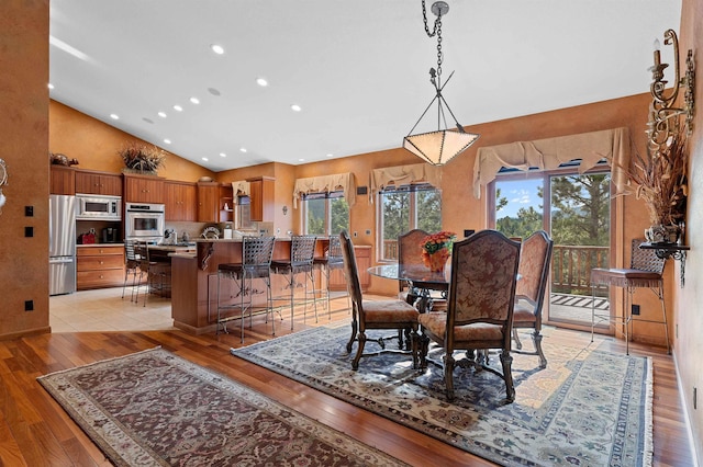 dining area featuring high vaulted ceiling and light hardwood / wood-style flooring