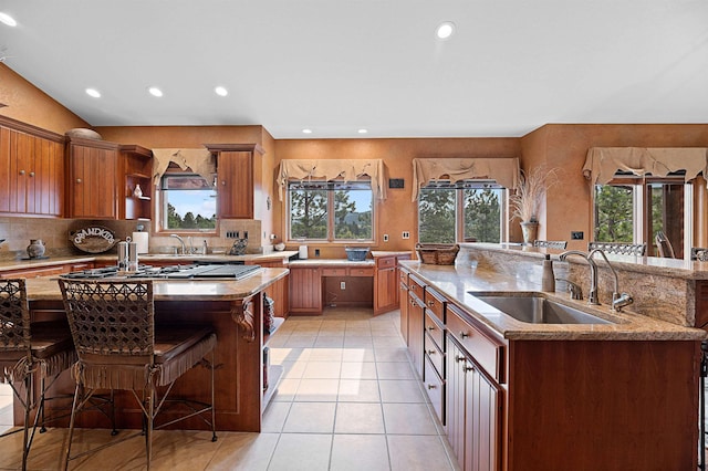 kitchen featuring a breakfast bar, a kitchen island with sink, sink, and light tile patterned floors