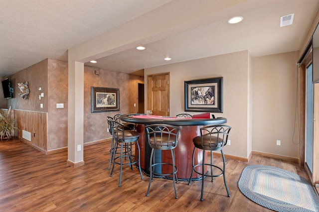 bar with wood-type flooring and a textured ceiling