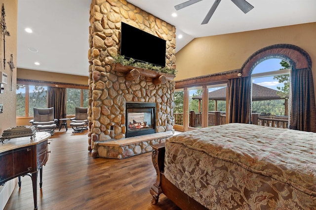 bedroom with multiple windows, ceiling fan, hardwood / wood-style floors, and a stone fireplace